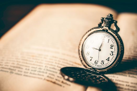 Antique clock placed on the book - vintage style.