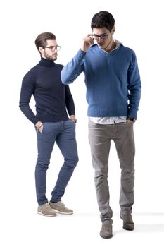 Two good-looking young men with eye-glasses in stylish clothes. Full figure studio shot, isolated on white