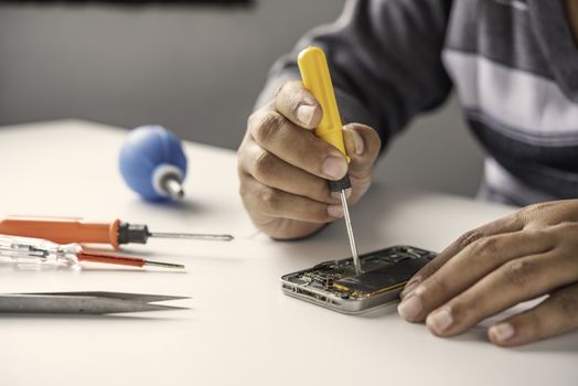 Repairman disassembling Repairman disassembling smartphone with screwdriver.