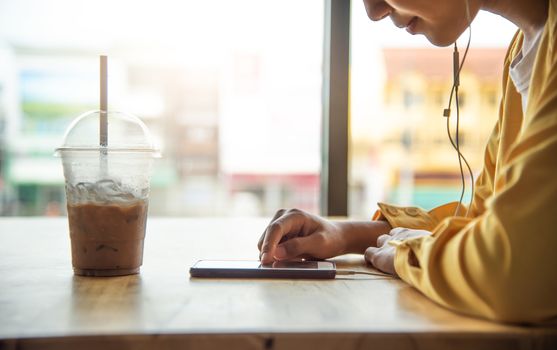 The girl is enjoying the phone in coffee cafe and have a glass of cold drink in a foreground