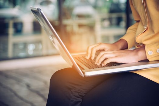 Playing a laptop on a lap in an open area.