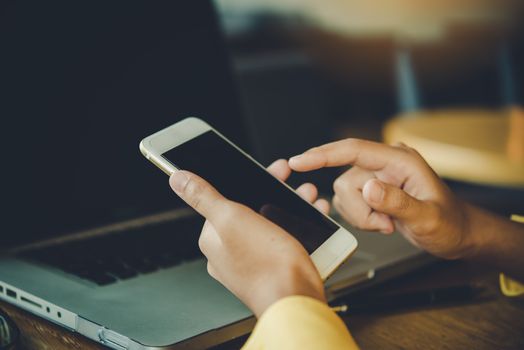Businessmen use smartphones and laptop to connect and find information in office