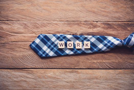 Necktie and the message "work" put on wooden floor - Concept of lifestyle for businessman.