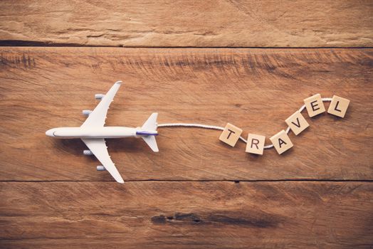 Airplane with the text "Travel" placed on a wooden floor. Travel ideas