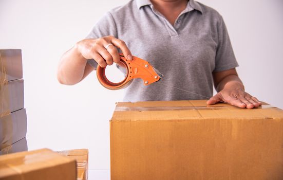 Hand holding closed-up tapes to pack products to prepare shipments.