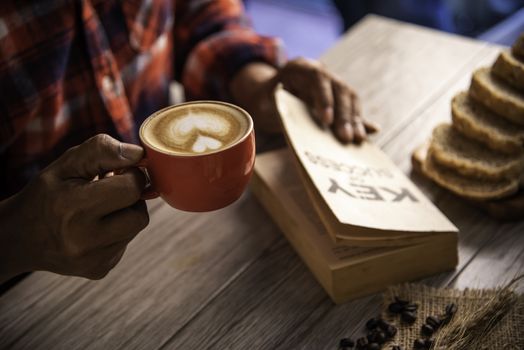 Hand holding a cup of coffee and reading a book key of success - concept lifestyle