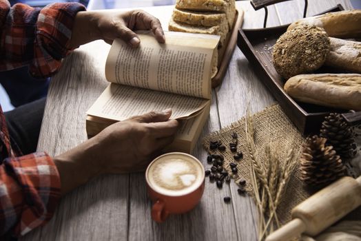 Hand holding a cup of coffee and reading a book key of success - concept lifestyle