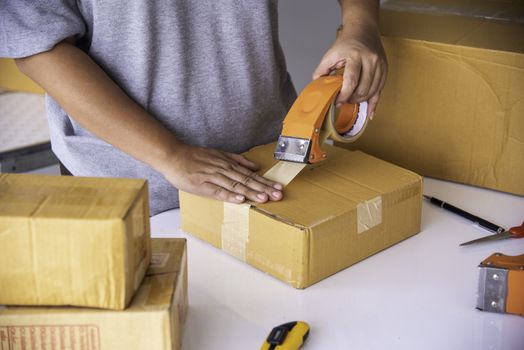 The staff is using the tape to pack the package goods to the customer.