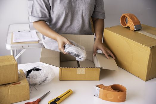 The staff is using the tape to pack the package goods to the customer.