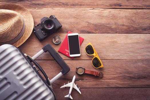 Clothing traveler's Passport, wallet, glasses, smart phone devices, on a wooden floor in the luggage ready to travel.