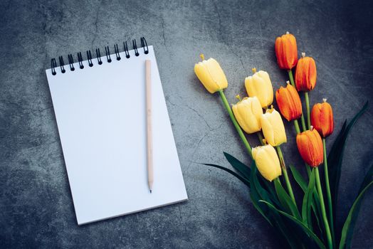 notebook ,pencil and flower on black background