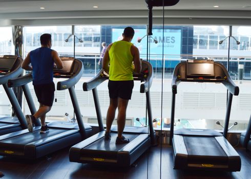 Modern gym with treadmills, people do sports on a cruise ship, the view from the back. MSC Meraviglia, 8 October 2018.