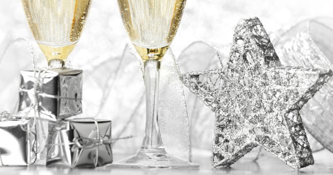 Glasses of champagne and christmas decoration on silver background