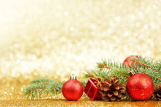 Christmas card with fir tree branch and decoration on golden glitter background