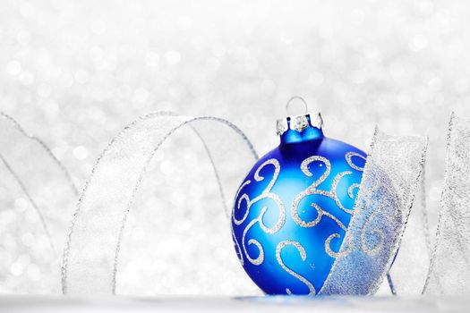 Blue Christmas ball and ribbon on abstract glitter silver background