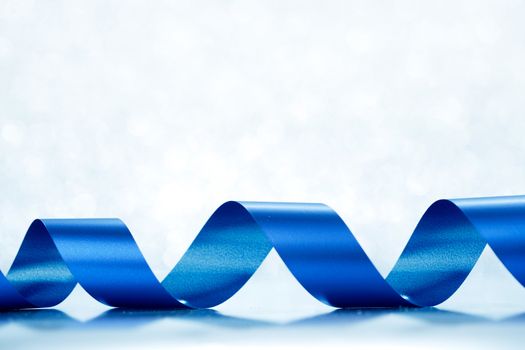 Curly blue gift ribbon on shiny background close-up