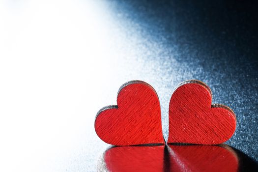 Two wooden red painted Valentine day hearts on metal background