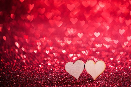 Two wooden hearts on red glowing bokeh hearts background for Valentines day