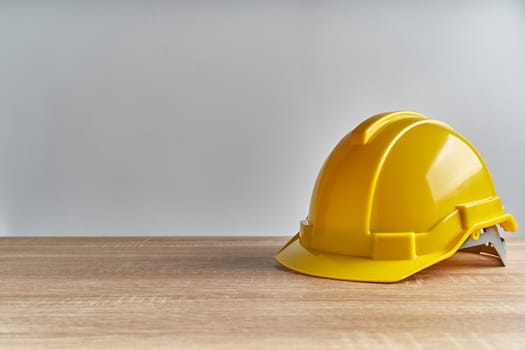 Yellow engineer hat place on wooden table with white background and copy space. Industrial successful concept photography.