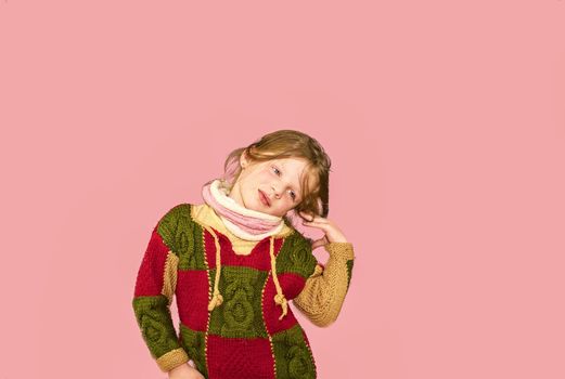Little girl on colourful background. Copy space. Young girl is wearing sweater. Soft pink background.