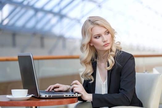 Young business woman wearing suit using laptop computer. Female working on laptop in cafe