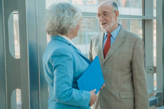 Senior business people discuss documents in modern business center