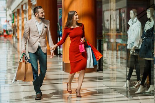 Happy beautiful young couple with shopping bags in mall