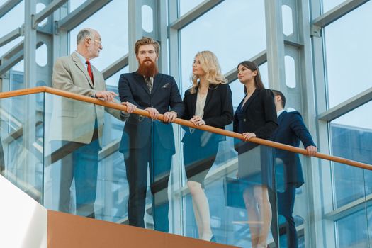 Business team standing on a balcony in modern glass office building