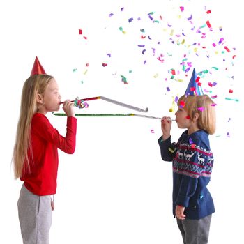 Children blowing party trumpets with confetti celebrating new year