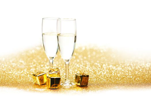 Champagne in glasses and gift box on golden background