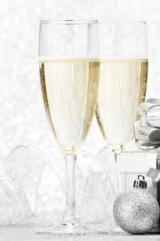 Two champagne glasses and christmas decoration on silver bokeh background