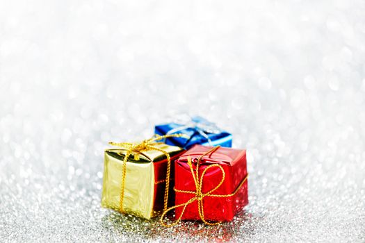 Holiday gifts in colorful boxes on silver bokeh background