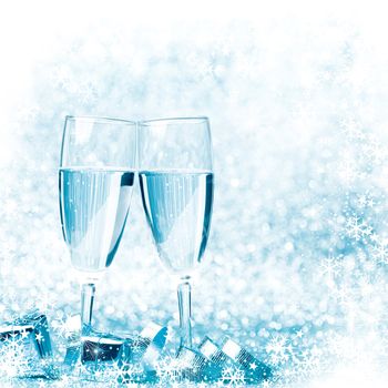 Glasses of champagne and silver gifts on glitter background