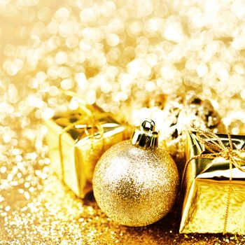 Golden Christmas ball and gifts on abstract glitter background