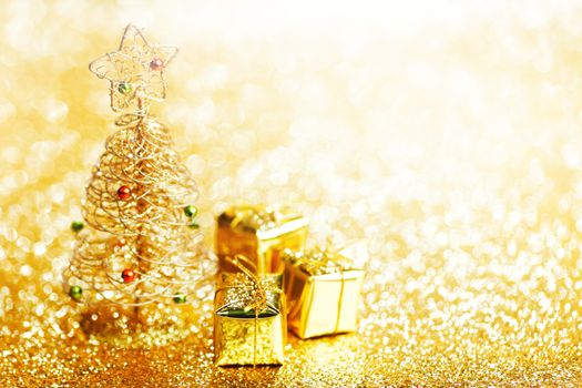 Beautiful golden decorative christmas tree and gifts on golden glitter background