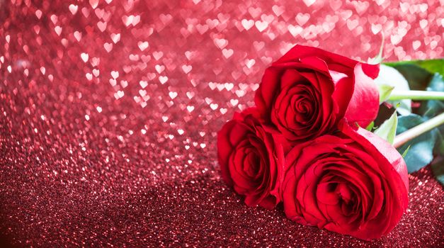Three beautiful red roses on heart shape bokeh glitter background
