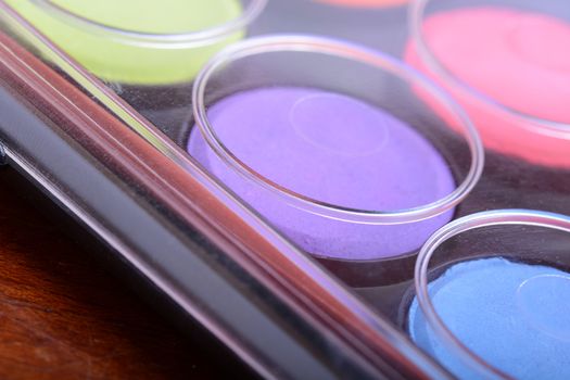 Paint pots in assorted colors. close up on wooden plate