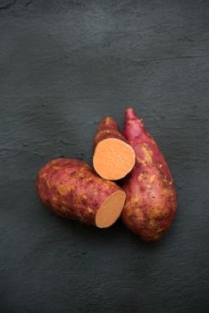 Raw sweet potatoes on wooden background close up. Top view.