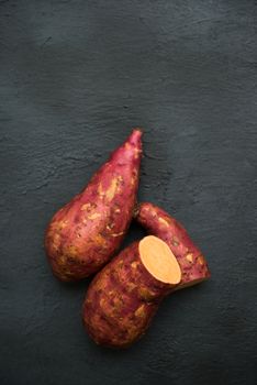 Raw orange sweet potatoes on dark background, Top view close up.