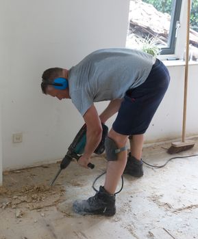 Construction concept - Jackhammer, removing chipboard from the floor - Selective focus