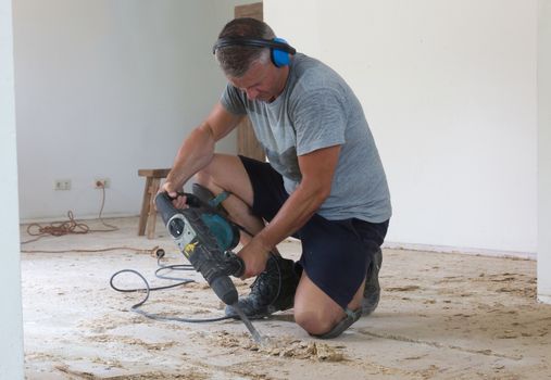 Construction concept - Jackhammer, removing chipboard from the floor - Selective focus