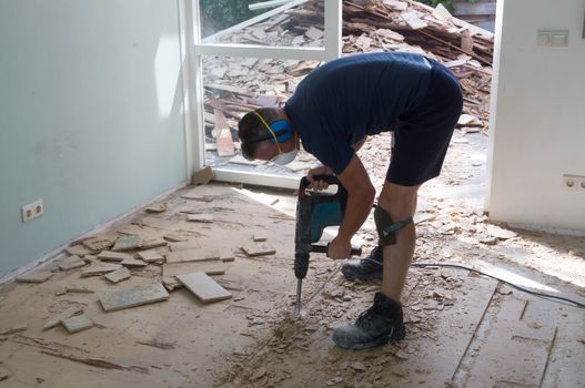 Construction concept - Jackhammer, removing chipboard from the floor - Selective focus