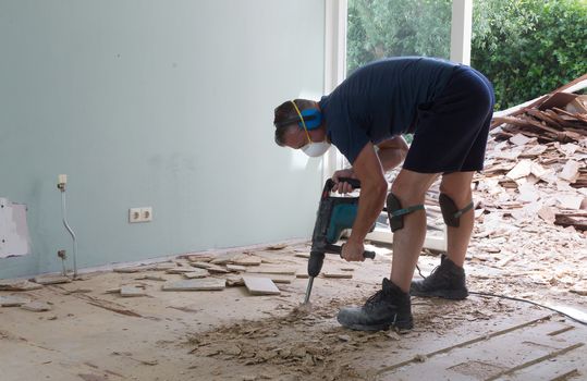 Construction concept - Jackhammer, removing chipboard from the floor - Selective focus