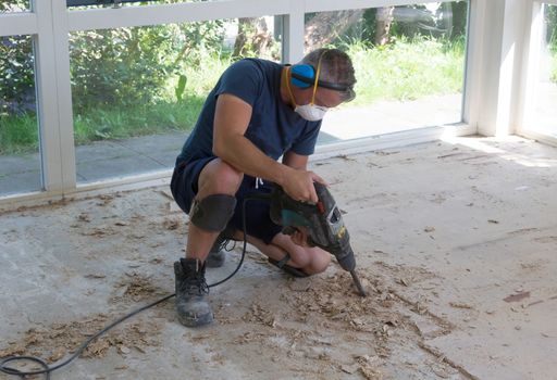 Construction concept - Jackhammer, removing chipboard from the floor - Selective focus