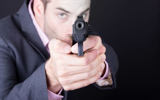 Man in suit with gun, isolated on black