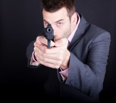 Man in suit with gun, isolated on black