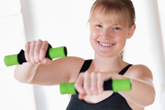 Young happy girl doing dumbbell exercises at home