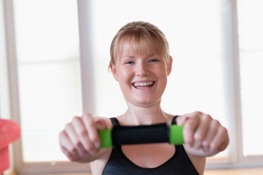 Happy young girl doing crunch exercises with a dumbbell