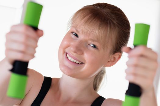 Young happy girl doing dumbbell exercises at home