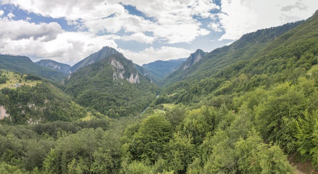 Mountain range and small village houses in green forest near Tara river canyon, view from Djurdjevica Tara Bridge, Montenegro